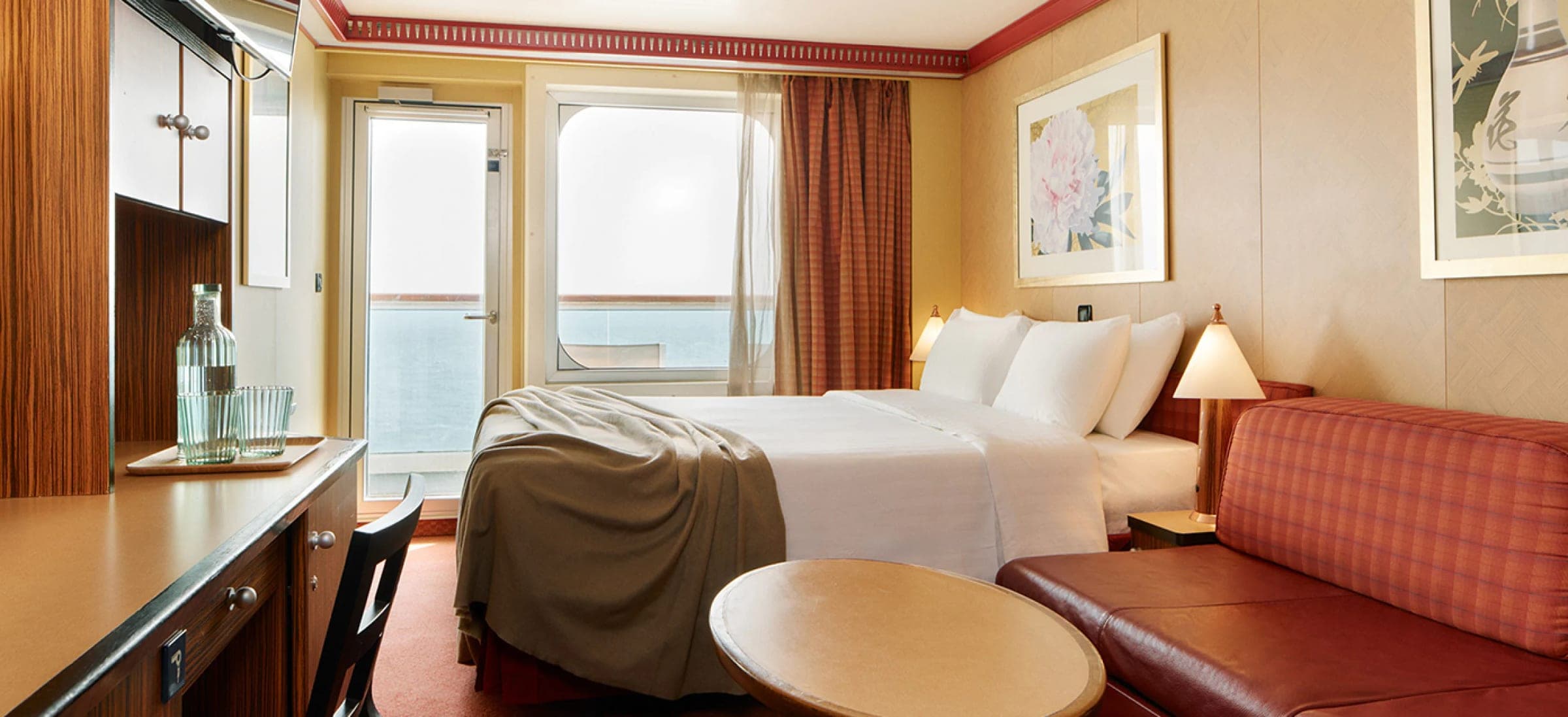 Cabina con balcón del Costa Serena: puerta vidriada al balcón con vista al mar, cama matrimonial y sofá