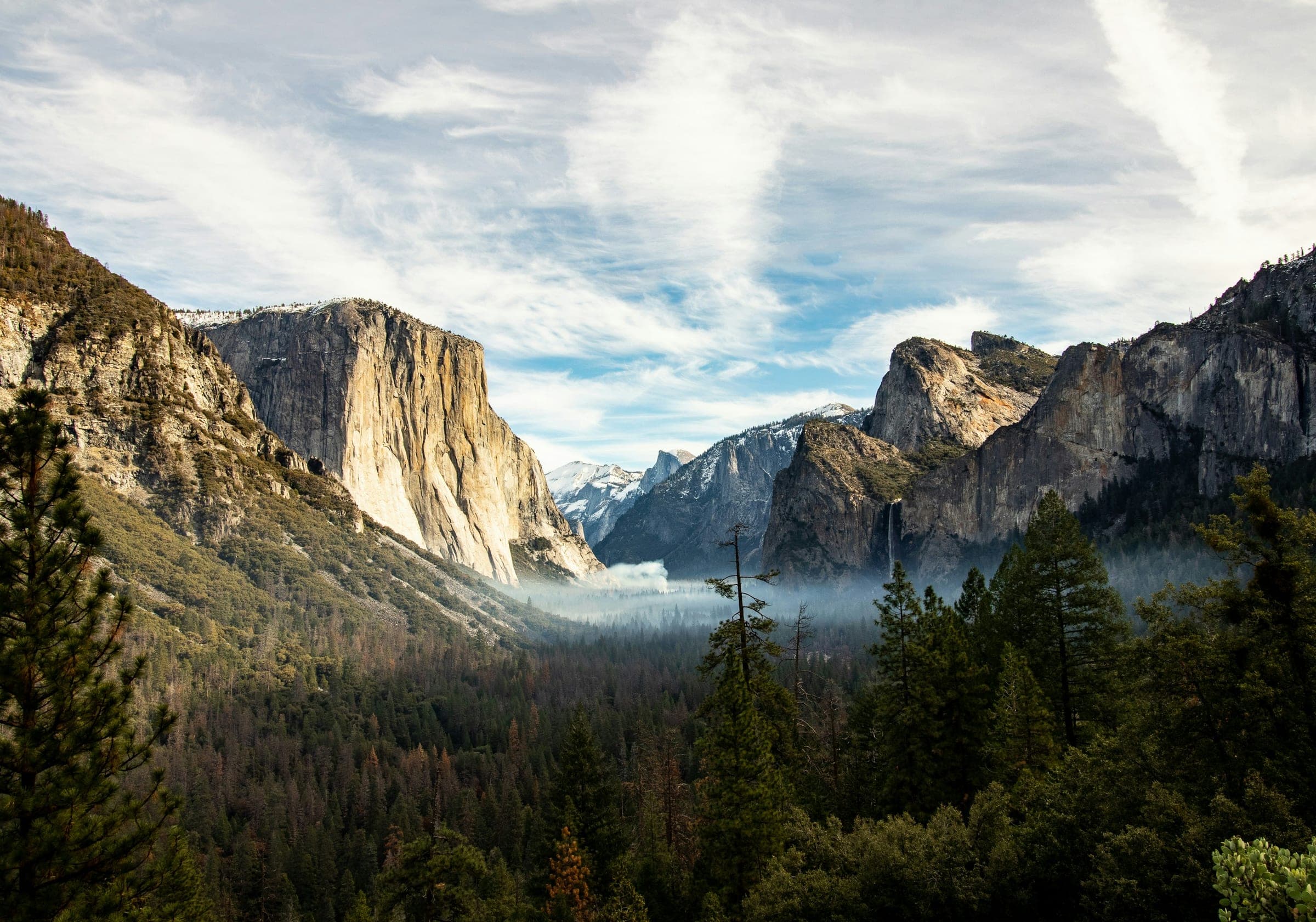 Valle de Yosemite entre paredes de granito, con una cascada angosta y bosque de pinos