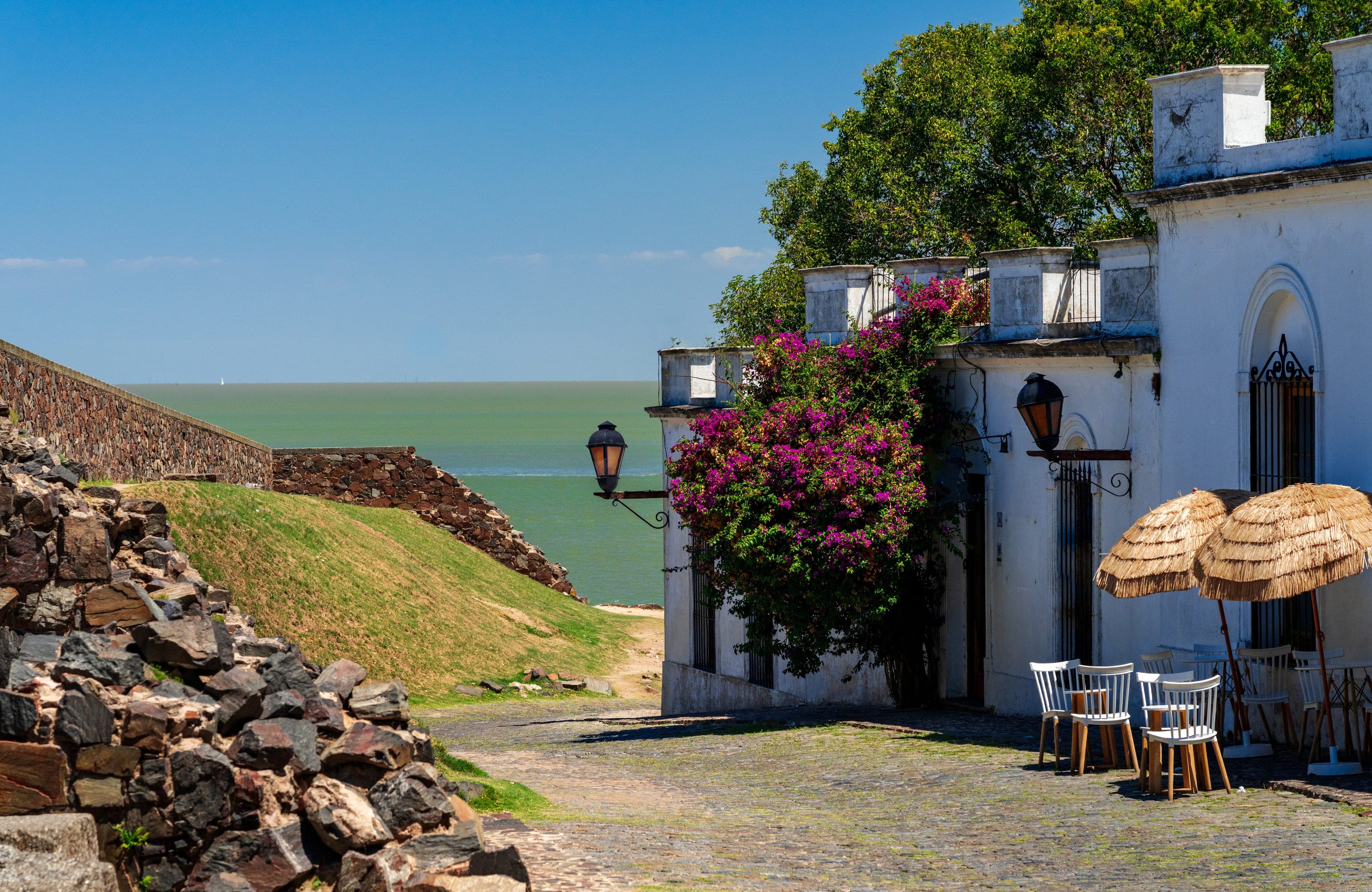 Calle de adoquines del barrio histórico de Colonia del Sacramento, con una casa blanca y buganvillas