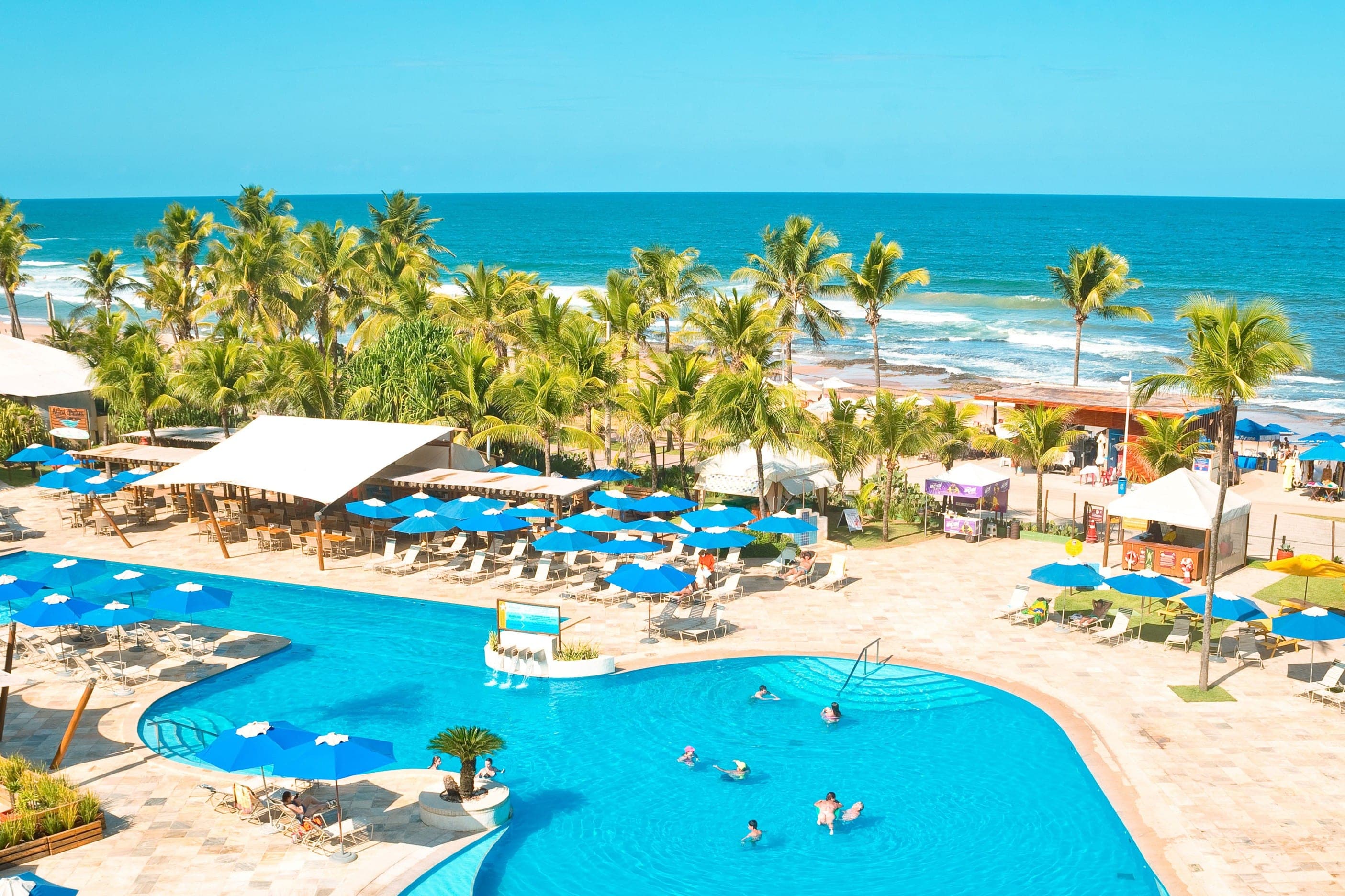 La pileta del hotel con palmeras y el mar detrás, en Salvador de Bahía